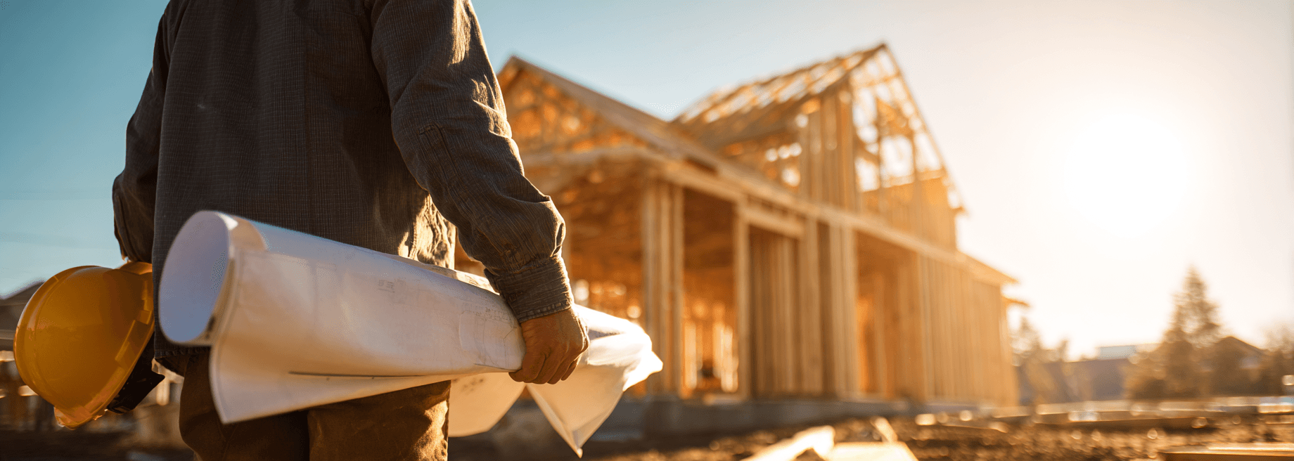 Contractor on a residential job site reviewing blueprints at golden hour